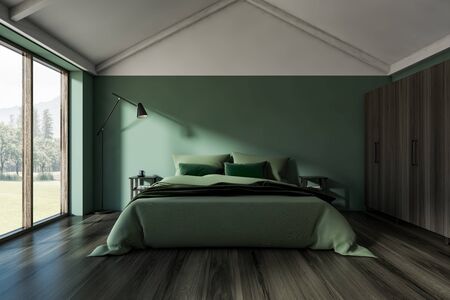 Interior of stylish attic bedroom with green walls, dark wooden floor, large window and double bed with two bedside tables and floor lamp. 3d renderingの写真素材