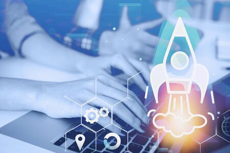 Hands of business people working with laptop in blurred office with double exposure of startup hologram. Concept of business idea. Toned imageの写真素材