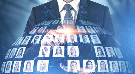 Businessman using tablet computer over blurred background with double exposure of diverse people portraits. Concept of social media. Toned imageの写真素材