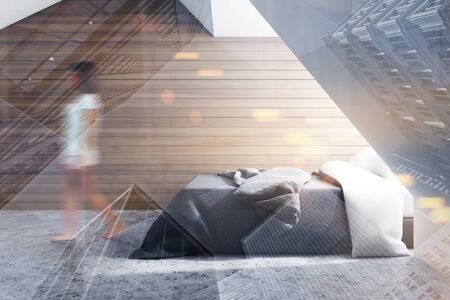 Young woman walking in minimalistic bedroom with white and wooden walls, concrete floor and king size bed with gray blanket. Toned image double exposure blurredの写真素材