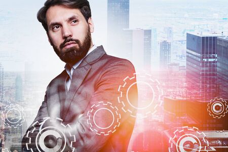 Serious bearded manager standing in city with double exposure of gears. Concept of leadership and...