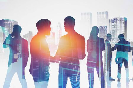 Silhouettes of business people working in modern city with double exposure of business interface. Concept of hi tech. Toned imageの写真素材