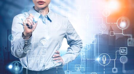 Unrecognizable young businesswoman working with futuristic immersive business interface in modern city. Concept of internet connection and hi tech. Toned image double exposureの写真素材