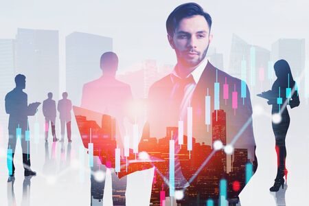 Confident young business leader with laptop and his team working in modern city with double exposure of graphs. Concept of leadership and stock market. Toned imageの写真素材