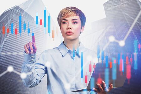 Beautiful young business consultant with laptop working with digital graphs in city. Concept of...