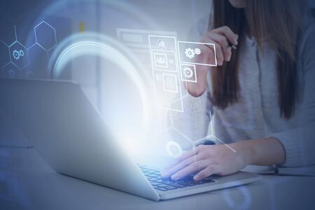 Young woman working with laptop in office with double exposure of HUD digital interface. Concept of...