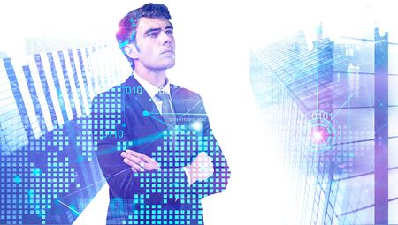 Confident young businessman standing with crossed arms in modern city with double exposure of digital wold map and HUD interface. Concept of hi tech and leadership. Toned imageの写真素材