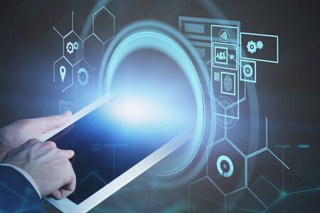 Hand of businessman using tablet computer with double exposure of HUD digital interface. Concept of...