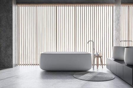 Interior of modern bathroom with concrete walls and floor, panoramic window, comfortable bathtub and...