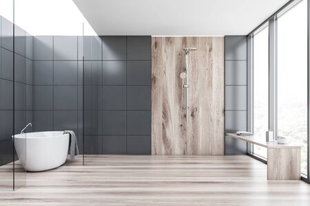Interior of comfortable bathroom with grey tile and glass walls, wooden floor, comfortable bathtub with towel hanging on it and vertical shower with wooden bench. 3d renderingの写真素材