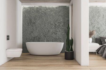 Interior of modern bathroom with white and crude gray walls, wooden floor, comfortable bathtub, toilet and master bedroom next to it. 3d renderingの写真素材