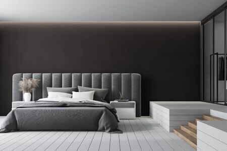 Interior of minimalistic master bedroom with black walls, comfortable king size bed with two bedside tables and soft gray headboard and wardrobe with stairs near it. 3d renderingの写真素材
