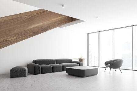 Corner of spacious living room with white walls, concrete floor, gray sofa and armchair near coffee...