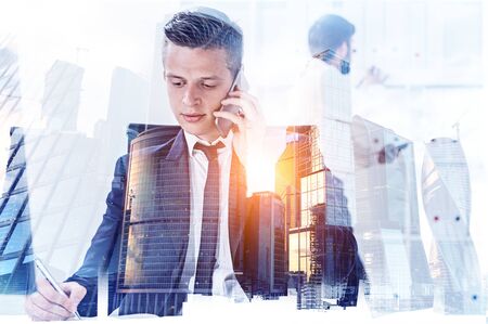 Young CEO and his colleague working together in office with double exposure of Moscow city panorama. Concept of teamwork and collaboration. Toned imageの写真素材