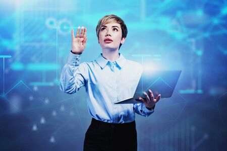 Young businesswoman with laptop working with blurry network interface. Concept of computer science...