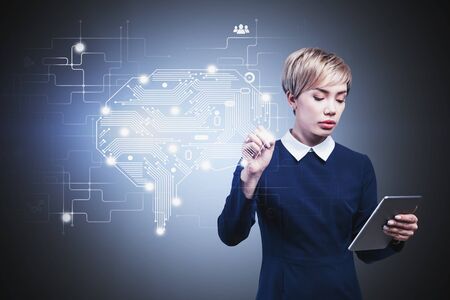 Serious young Asian woman with tablet working with AI brain interface. Concept of internet of...