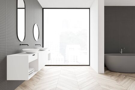 Interior of loft bathroom with gray walls, wooden floor, comfortable gray bathtub, double sink and window with blurry cityscape. 3d renderingの写真素材