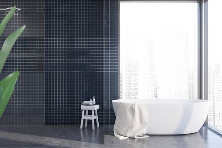 Interior of spacious panoramic bathroom with blue tile walls, comfortable bathtub and glass wall...