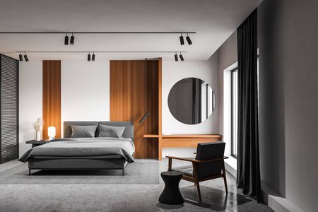 Interior of luxury master bedroom with white and wooden walls, concrete floor, comfortable king size...