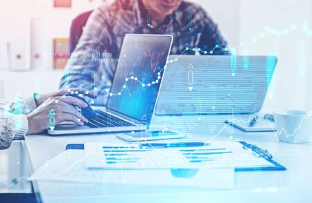 Unrecognizable business people using laptops in blurry office with double exposure of digital...