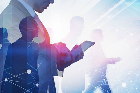 Side view of businessman using tablet computer in city with double exposure of cityscape and blurry network interface. Concept of smart city. Toned imageの写真素材