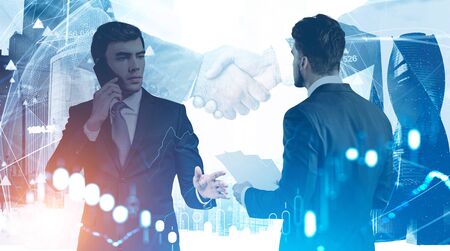 Two successful businessmen in city with business people shaking hands in background and double...