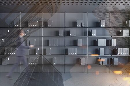 Blurry young businessman walking in modern office with grey walls, carpeted floor and bookcase with folders. Concept of paperwork and archive. Toned image double exposureの写真素材