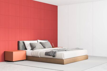 Corner of stylish minimalistic master bedroom with red and white walls, concrete floor, comfortable king size bed and orange bedside tables. 3d renderingの写真素材