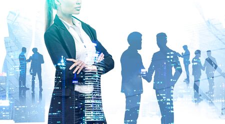 Unrecognizable confident businesswoman standing with crossed arms with her colleagues in background and double exposure of blurry night cityscape. Concept of leadership. Toned imageの写真素材