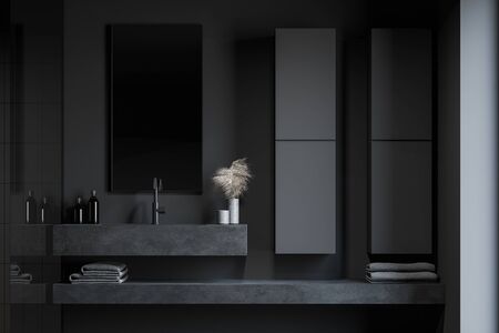 Close up of massive stone sink standing in loft bathroom with dark grey walls, comfortable cabinets and vertical mirror. Shelf with folded towels. Concept of spa. 3d renderingの写真素材