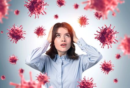 Portrait of scared young European businesswoman with viruses around her. Concept of coronavirus ncov...