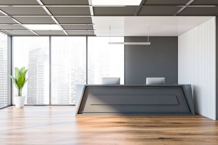 Comfortable gray reception desk with computers standing in stylish corporate office with white and grey walls and panoramic window with blurry cityscape. 3d renderingの写真素材