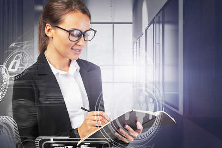 Beautiful young woman CEO in glasses writing in office hall with double exposure of blurry...