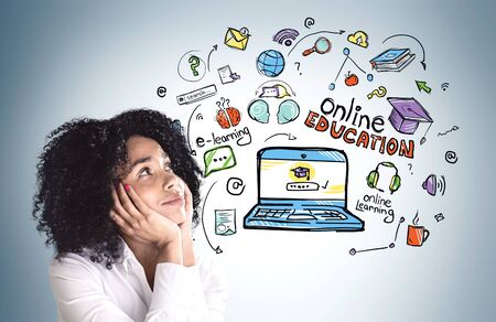 Portrait of dreamy young African American woman looking at colorful online education sketch on grey...
