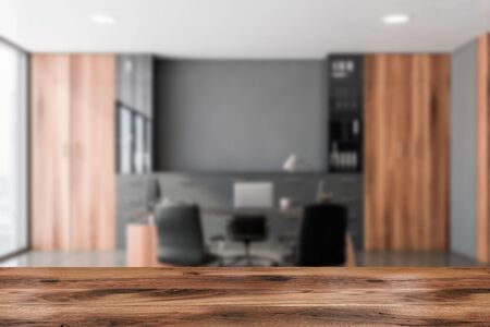 Wooden table for your product in blurry luxury CEO office with gray walls, tiled floor, computer...
