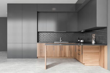 Interior of stylish kitchen with grey walls, concrete floor, wooden countertops with built in sink and cooker, grey cupboards and island. 3d renderingの写真素材