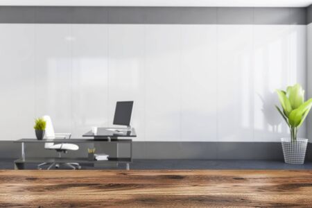 Wooden table for your product in blurry minimalistic CEO office with white and gray walls, concrete floor and stylish computer table with white chair. 3d rendering mock upの写真素材