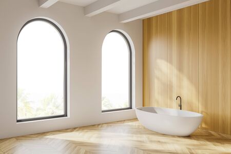 Corner of stylish bathroom with white and wooden walls, wooden floor, arched windows with blurry tropical view and comfortable bathtub. 3d renderingの写真素材