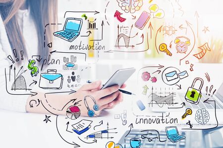 Unrecognizable young businesswoman using smartphone in blurry office with double exposure of colorful business plan sketch. Concept of business strategy. Toned imageの写真素材