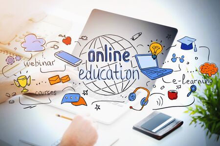 Hands of unrecognizable man using laptop and taking notes at blurry table with double exposure of bright online education sketch. Concept of knowledge, development and technology. Toned imageの写真素材