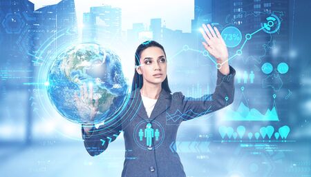 Beautiful young businesswoman working with immersive business infographics interface in blurry city...