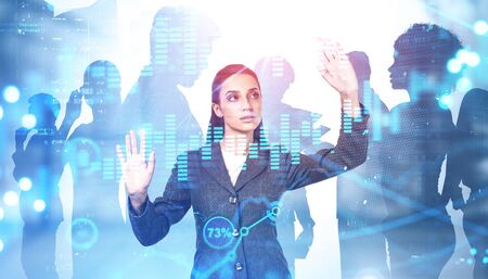 Young businesswoman using digital graph in blurry city with double exposure of her diverse team. Concept of stock market and leadership. Toned image.の写真素材