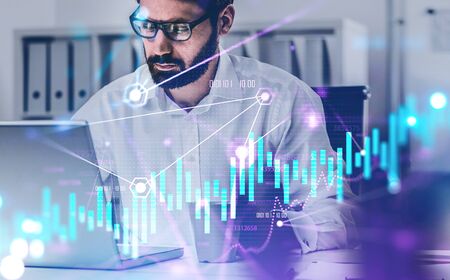 Portrait of bearded young trader in glasses working in blurry office with double exposure of...