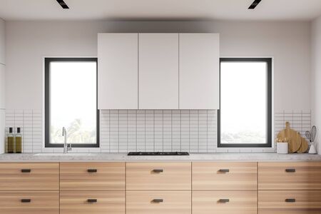 Close up of wooden countertop with built in cooker and sink standing in modern kitchen with white walls and windows with blurry tropical view. 3d renderingの写真素材