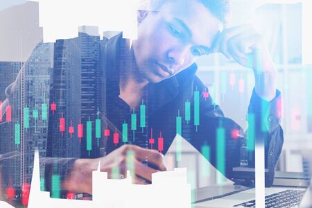 Serious young African American trader working in his office with double exposure of blurry abstract...