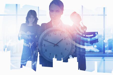 Businesswoman with big clock and her diverse colleagues working together in blurry panoramic office...