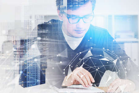Serious young European businessman in glasses working in blurry office with double exposure of abstract cityscape and network interface. Concept of big data and hi tech. Toned imageの写真素材