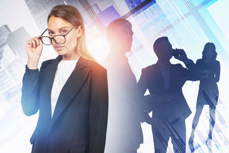 Beautiful young businesswoman in glasses and her diverse team working together in blurry abstract city. Concept of teamwork and leadership. Toned image double exposureの写真素材