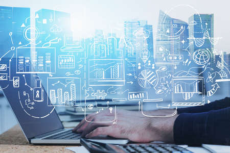 Hands of businessman typing on laptop in blurry office with double exposure of abstract cityscape and creative business sketch. Concept of planning. Toned imageの写真素材