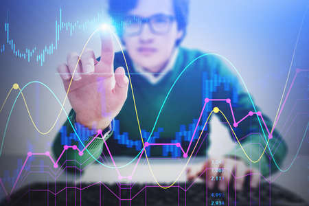 Blurry young European businessman in glasses using financial interface at office table. Concept of...
